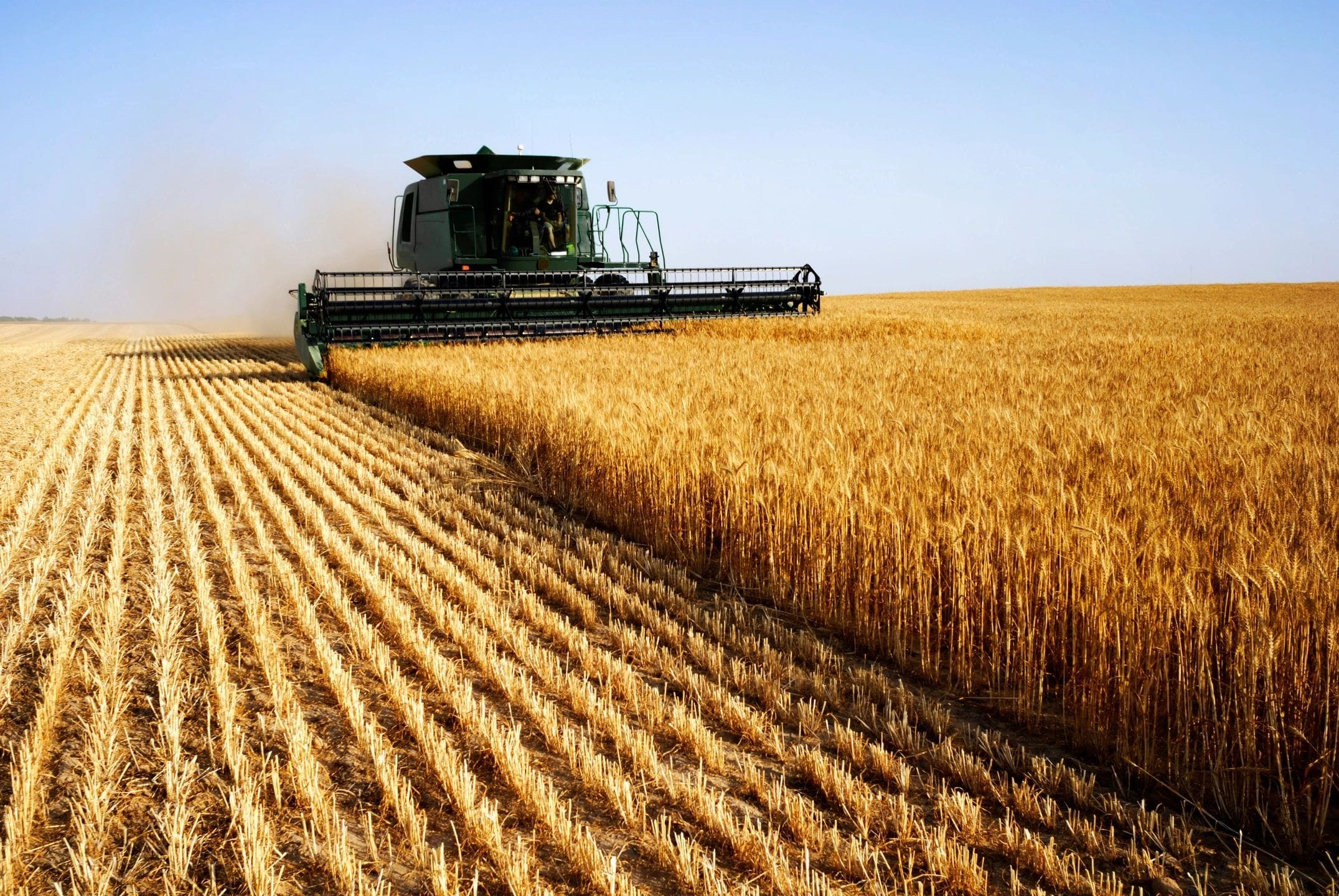 A large green machine is in the middle of a field.