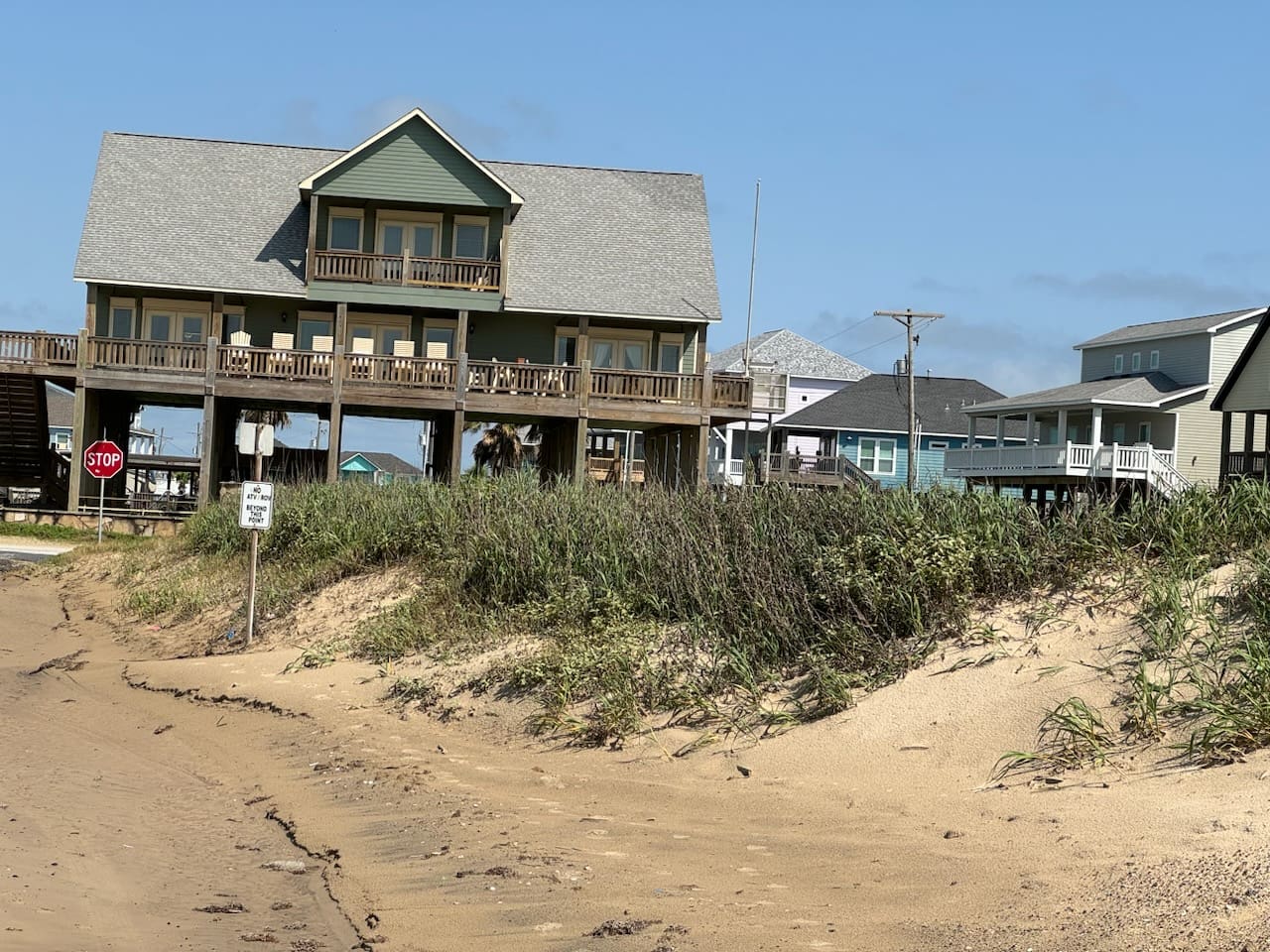 A house on the beach with many windows and doors.